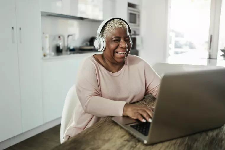 Woman wearing headphones while using a laptop